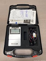 TENS 7000 device and accessories inside carrying case, manuals on top
