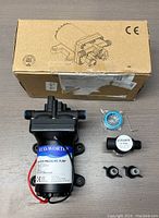 ECO-WORTHY water pressure pump laid flat beside its cardboard box and included accessories to display entire package contents.