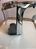 Side view showing transparent soap reservoir, sensor, and battery compartment area with usage instructions on label.