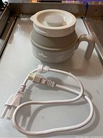 Bear foldable electric kettle fully assembled with lid on and power cord disconnected on a metal surface.