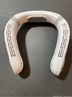 Top view of the white U-shaped cooling cordless neck fan showing vented slits for airflow.