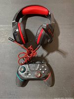 Photo showing front view of wired gaming headset and wireless gaming controller on black surface.