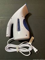 Full side view of white and blue handheld garment steamer showing ergonomic handle and water reservoir.