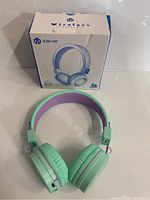 iClever kids wireless headphones in green and purple color, shown with their original box in front on a white surface.