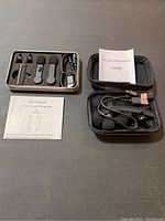 Two wireless lapel microphone sets shown with all accessories including microphones, foam windshields, clips, USB charging cables, and user manuals inside protective cases.