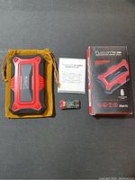 The red and black Fuzion FU-200 Professional Digital Scale with protective cover, yellow pouch, user manual, calibration weight, and two AAA batteries displayed on a flat surface.