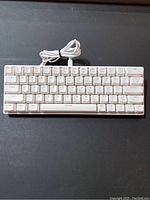 Top front view of white wired mechanical keyboard with cable coiled on top