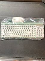 Photo of wireless keyboard and mouse combo in plastic wrapping on black surface