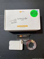 Package box for Luminoodle Click 3-pack stick-on LED strips with a USB-powered control box and LED strip roll displayed in front.