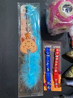 Photo of blue feather cat teaser wand, blue and red bell collars with paw prints.