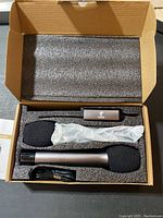 Open Tonor microphone set box showing two wireless microphones with foam windscreens, a receiver, USB cable, and manual fitted inside protective foam packaging.