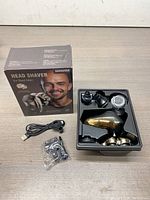 Shpavver MS-672 Head Shaver displayed alongside box, USB charging cable, and attachments arranged in molded tray