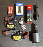 Overview photo showing all items in the bundle arranged on a flat surface, clearly displaying headlamps, flashlight, chargers, USB cable, and batteries.