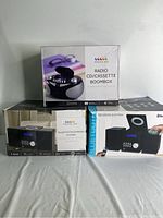 Three boxed audio systems grouped: two Proscan Bluetooth CD Micro Systems and one Proscan Radio CD/Cassette Boombox.