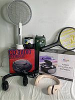 Photo showing the boomboxes boxes, handheld bug zappers, neck fans, headlamp and solar animal repeller devices grouped together.