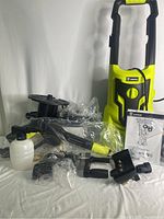 Multiple accessories including spray gun, nozzles, foam cannon, hose reel, and connectors, mostly in protective plastic.