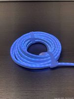 Coiled LED strip light turned off on a dark surface, showing the translucent sheath and fastening bands.