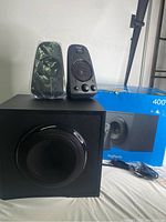 Photo showing the Logitech speaker system box, two satellite speakers and one subwoofer on a white surface