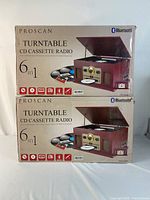 Two boxed Proscan 6-in-1 turntable and audio systems stacked, showing packaging and box art.