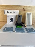 Photo of the wireless charger, earbuds box, stylus pen box, power bank, green battery, and flip phone on charging dock