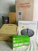 Photo of all items boxed and arranged showing the cool mist humidifier box, solar fountain pump box, three-pack of WiFi smart plugs, and other smaller items boxes.