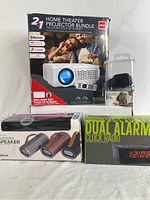 Photo of 2-in-1 home theater projector bundle with fold-up screen, Bluetooth speaker, and dual alarm clock radio in their original packaging.
