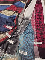 Five scarves laid flat showing patterns and pashmina labels