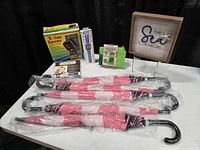 Table view showing five wrapped umbrellas, boxed accessories, wall art sign