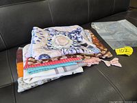 Stack of five folded shawls showing varied colours and patterns