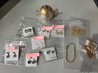 Group shot of all earrings in bags, bracelet, tassels, and trinket pot