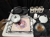 Overall lot view showing canisters, saucepan, tray, pans, juicer, dish, plate