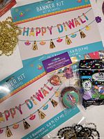 Close-up of both Happy Diwali banner kit packages with beads and balloons visible