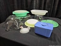 Group shot of all items including blue Hall dish, Tupperware set, ruffled glass bowl, milk glass hen, clear and green bakeware