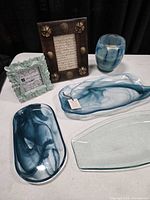 Group shot showing two blue swirl platters, clear tray, two frames, blue glass candle