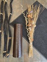 Close view of vase, one bundle of black reeds, mixed bundle with pods