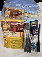 Two packaged DuPont Tychem QC coveralls, Shell Life Time manuals stack, IRWIN tape measure, ring mandrel, blue ring sizer loop, multi-tool