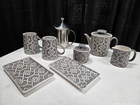 Full set displayed on table: milk frother, mugs, teapot, sugar bowl, creamer, plates