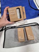 Full kit on blue drawstring bag showing box of wipes, solution bottle, brushes, mesh bag