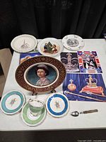 All items laid out on table including plates, teacup, saucers, spoon, booklets