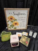 Framed sunflower print, wine glass box, green pouch, small plaque, napkins, two grey metal plaques