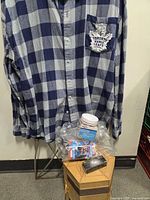 Plaid shirt on hanger with toolbox, flashlight box, tissue packs visible