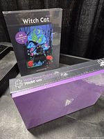 Front view of sealed Witch Cat jigsaw puzzle and side view of second sealed box