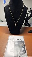 Full view of necklace displayed on black bust with GRA certification in foreground.