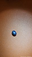Blue star sapphire gemstone seen from a slight top angle showing 6-ray star on surface