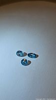 Three natural lagoon blue Cambodian zircon gemstones on white background, showing their color, cut, and clarity.