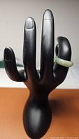 View of the jade ring displayed on a black hand mannequin showing the ring's fit and color.
