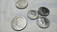 Top-down photo showing 1972 Eisenhower dollar coin, 1972 Kennedy half dollar, 1971 and 1974 Kennedy half dollars.