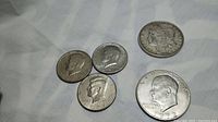 Photo showing the 1921 Morgan silver dollar, the 1972 Eisenhower dollar, and three Kennedy half dollar coins dated 1964, 1965, and 1968.