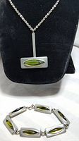 Front view of the pendant on a chain and the bracelet with green marquise shaped glass inserts in pewter rectangular frames.