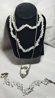 Sterling silver necklace with crystal pendant displayed on black stand alongside crystal chip necklace and bracelet.